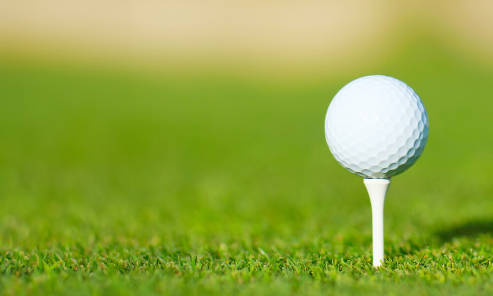 picture of a golf ball on a tee on green grass